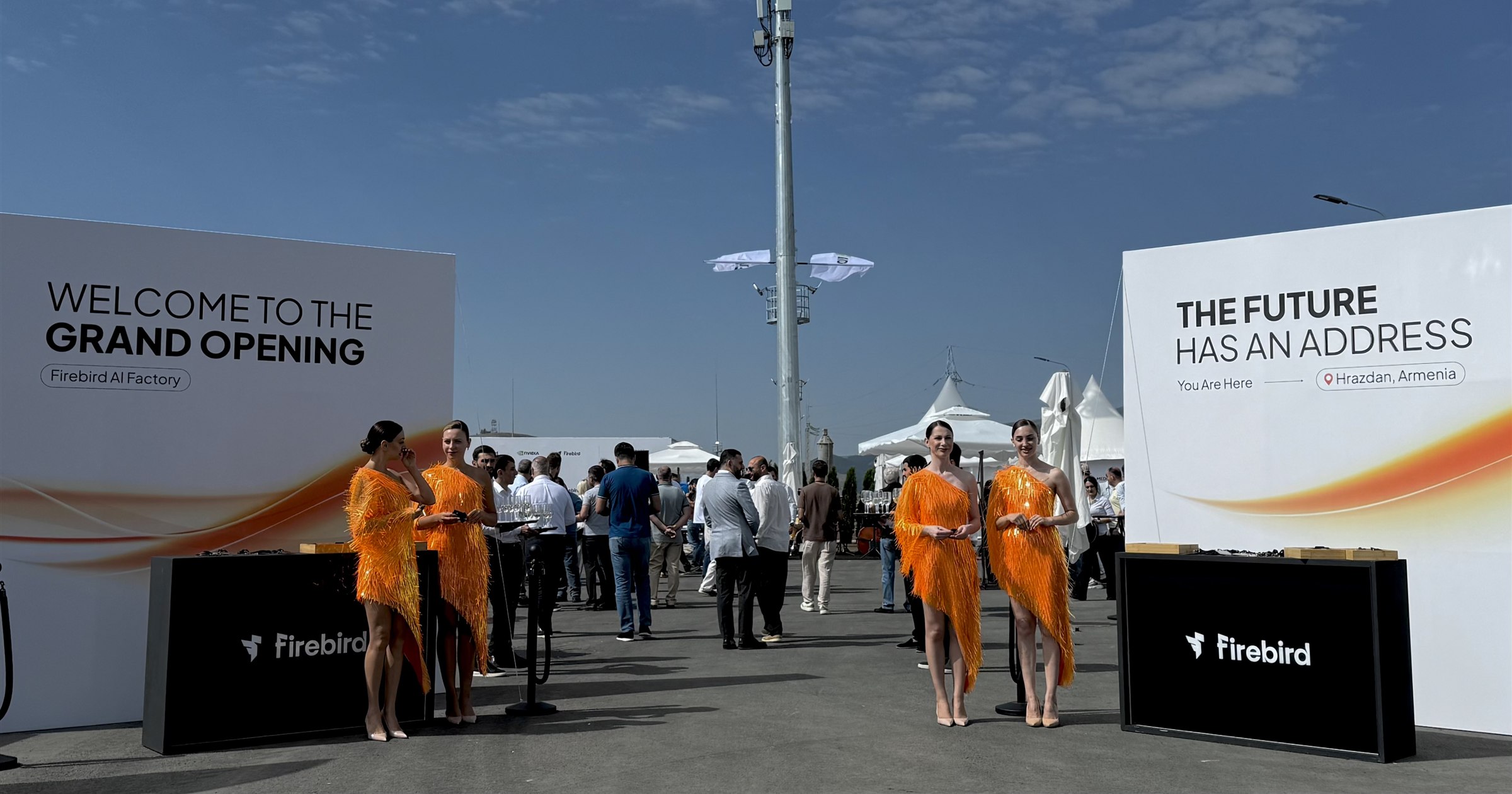 Signage at the entrance to the Firebird AI factory opening in Hrazdan: one board reads Welcome to the Grand Opening, the other reads The future has an address, you are here, Hrazdan, Armenia, with a mobile mast standing behind the guests.
