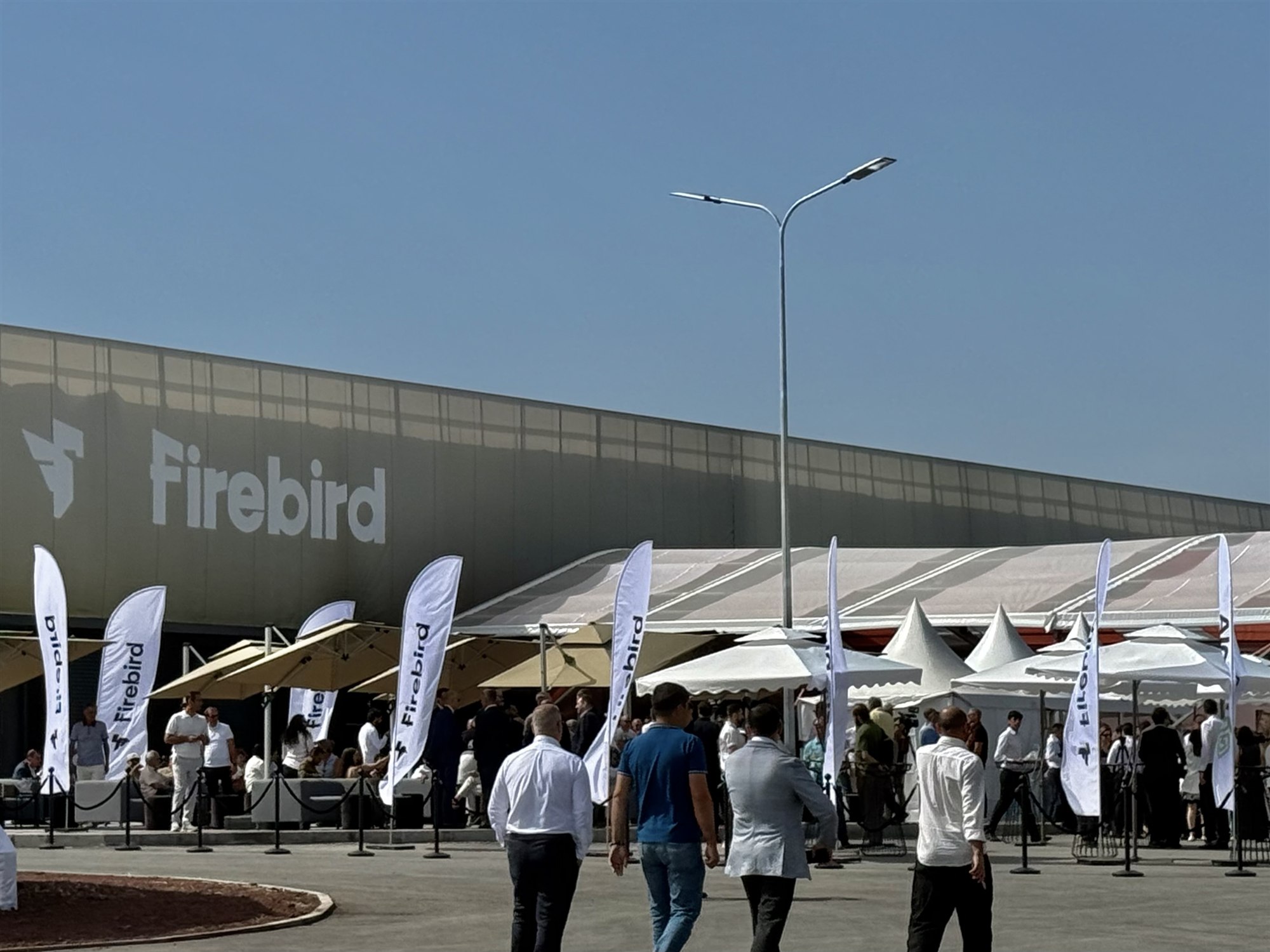 The Firebird building on opening day, with branded flags and guests arriving under canopies.