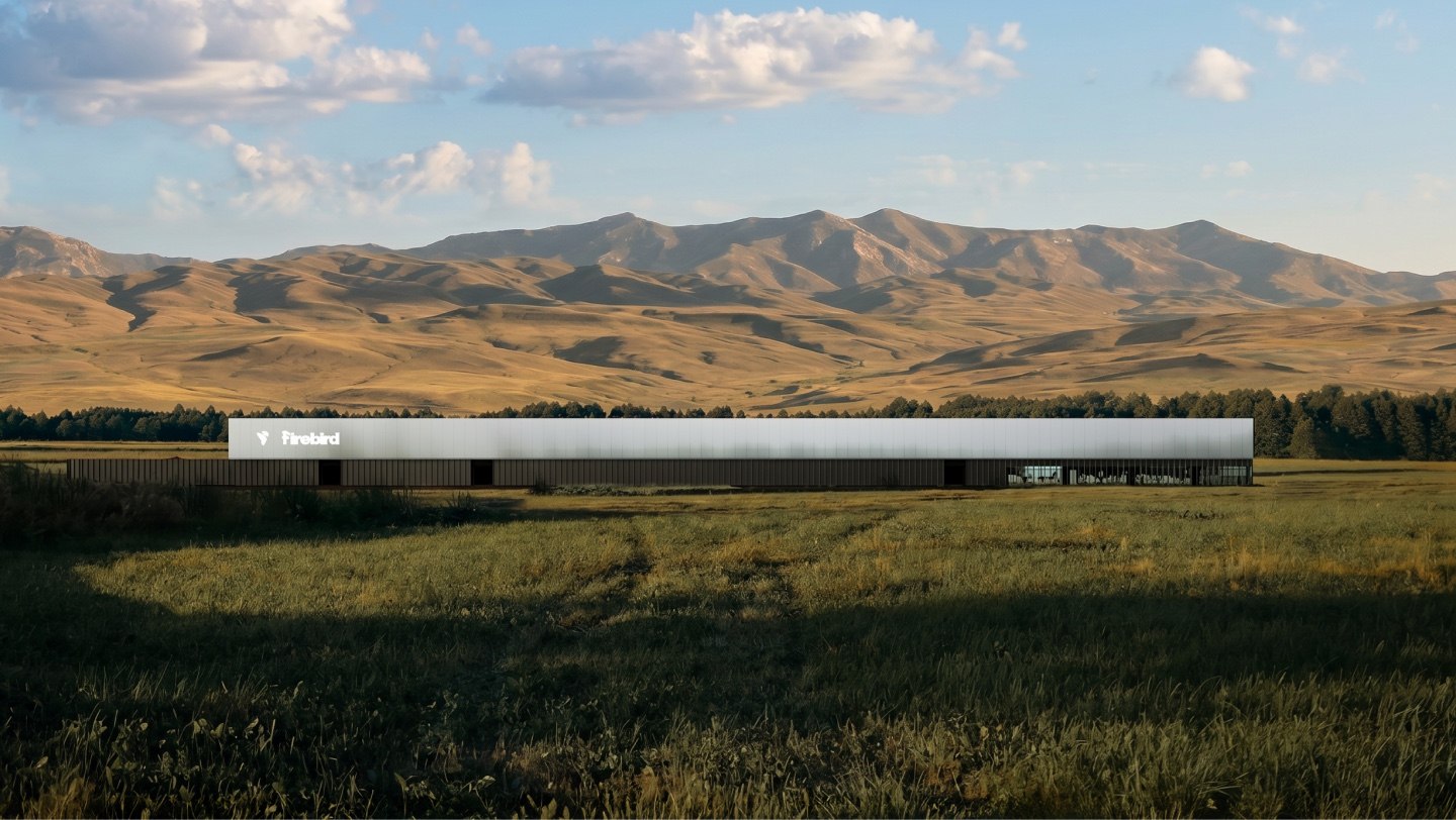 A long low white building with the Firebird wordmark, standing alone in a valley with bare mountains behind it.